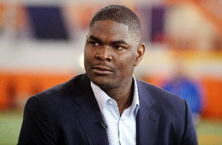 Keyshawn Johnson in a black coat poses for a picture.